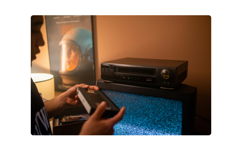 Man setting up a VCR to watch a cassette, highlighting vintage electronics popular in eBay reselling.